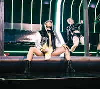 a woman in a black outfit is sitting on a stage