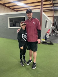 a man and a young boy posing for a photo in a baseball field