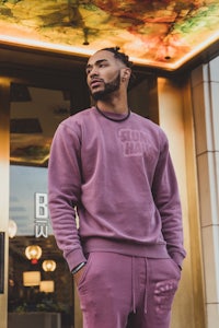 a man in a pink sweatshirt standing outside of a restaurant