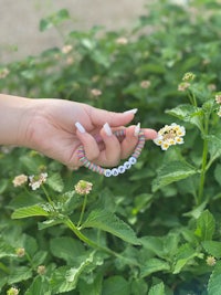 a woman's hand holding a bracelet with a flower on it