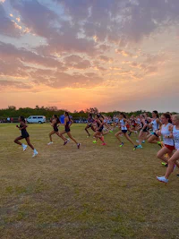 a group of people running in a field at sunset