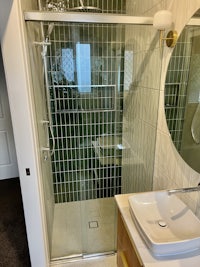 a bathroom with a green tiled shower stall and sink