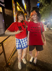 two women posing in front of a building at night