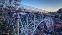 a bridge spanning over a canyon at sunset