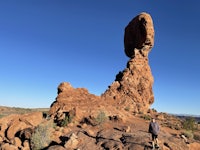 a man standing in front of a large rock formation