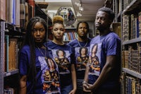 a group of people standing in a library wearing t - shirts