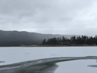 a lake covered in ice with trees in the background