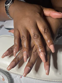 a woman's hands with nude nails and a watch