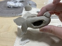 a person holding a clay fish with a hole in it