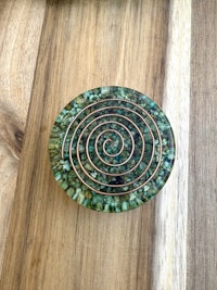 a green and copper spiral coaster on a wooden table
