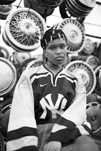 a black and white photo of a woman sitting in front of a bunch of tire rims