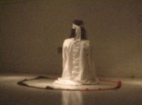 a woman in a white dress standing in a dark room