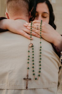 a man is hugging a woman with a rosary