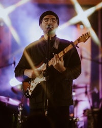 a man playing an electric guitar in front of a microphone