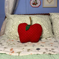 an apple shaped pillow on a bed
