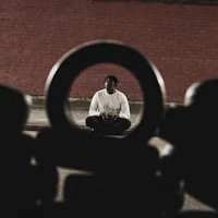 a man sitting on the ground in front of a circular hole
