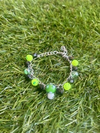 a bracelet with green and black beads on grass