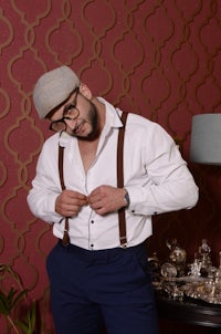 a man wearing suspenders and a hat