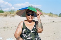 a woman with tattoos holding an umbrella on the beach