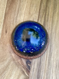 a blue and black glass sphere on a wooden table
