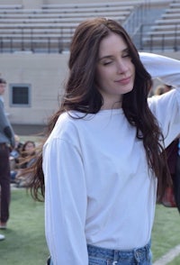 a woman in a white shirt and jeans standing on a field