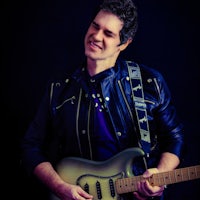 a man in a leather jacket holding a guitar