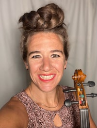 a woman holding a violin and smiling at the camera