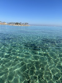 a view of a clear blue water with a beach in the background