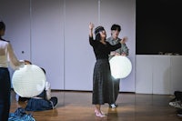 a group of people standing on a stage with paper lanterns