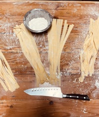 tagliatelle with a knife and flour on a wooden table