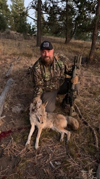 a man with a gun and a coyote in the woods