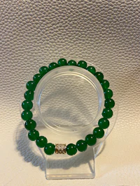 a green jade beaded bracelet on a white surface