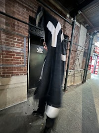a man in a black coat walking down the street
