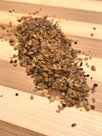 a pile of dried seeds on top of a wooden cutting board
