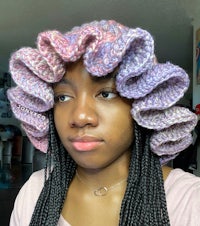 a black woman wearing a crocheted ruffled hat