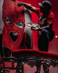 a man is painting a red mask on a canvas