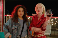 two women standing next to each other holding a glass of wine