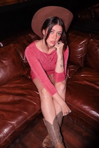 a woman in a cowboy hat sitting on a brown couch