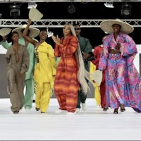 a group of people walking down a runway in colorful outfits