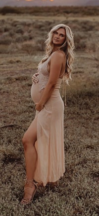 a pregnant woman posing in a field at sunset