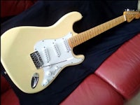 a white electric guitar sitting on top of a couch