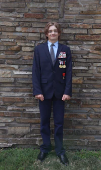 a young man in a suit standing in front of a brick wall