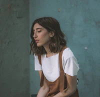 a young woman in overalls sitting on a bench