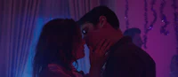 a man and woman kissing in front of a purple light