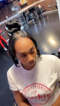 a woman sitting in a chair with her hair in a bun
