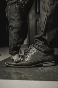 a black and white photo of a man standing next to a child's foot