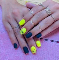 a woman's hands with yellow and black nails and rings