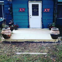 a blue house with a wooden deck and potted plants