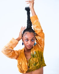 a black woman in a yellow top posing in front of a white background