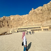 a woman is standing in front of a temple in egypt